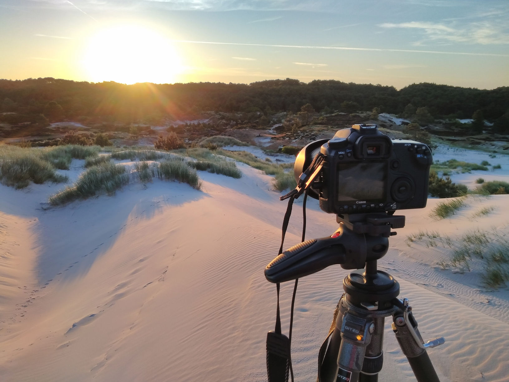 camera pointed at sunrise in dunes